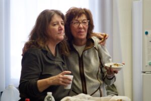 Two women hug as Tom O'Donnell speaks at The audience listens to Tom O'Donnell at St. Michael's Episcopal Church.